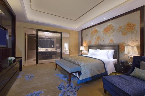 a bedroom with a bed and a tv and a couch at Wanda Vista Taiyuan in Taiyuan