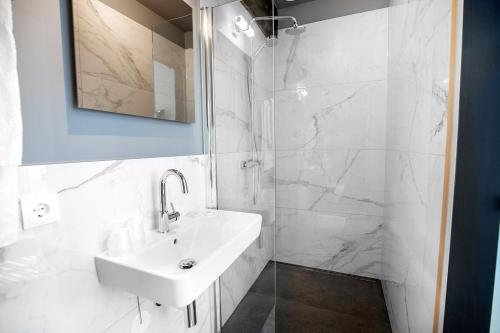 een witte badkamer met een wastafel en een douche bij Boutique hotel WKNDS in Leeuwarden