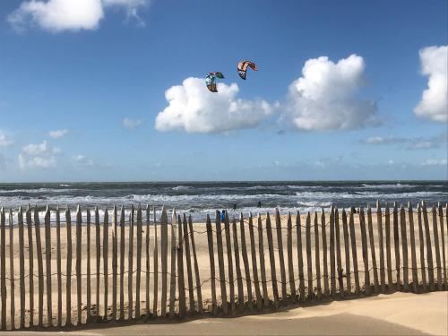 two kites flying in the sky over the beach at Bed and Breakfast Kik en Bun in Katwijk aan Zee