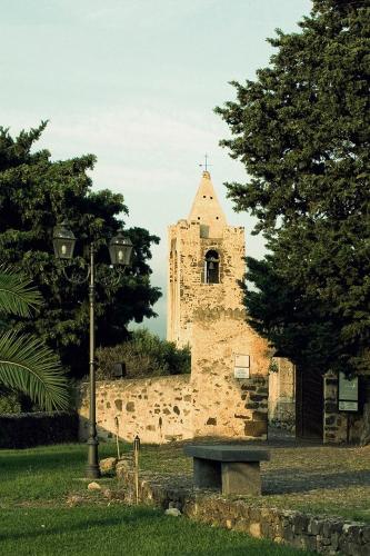 a stone building with a clock tower in a park at Castello Malicas in Galtellì