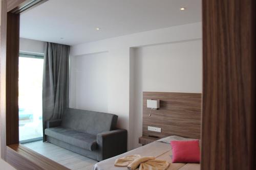 a bedroom with a chair and a mirror at Fedrania Gardens Hotel in Ayia Napa