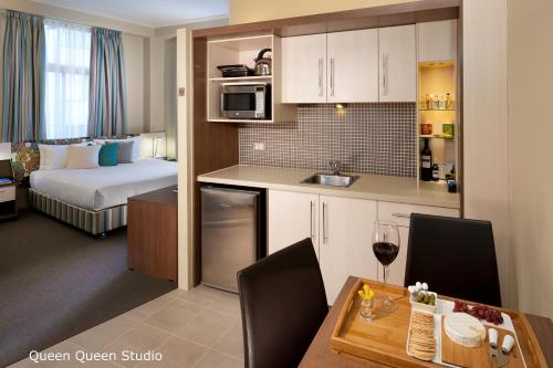 a room with a kitchen and a room with a bed at Best Western Plus Hotel Stellar in Sydney