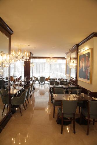 a dining room with tables and chairs and chandeliers at Grand Concerto Hotel in Beirut