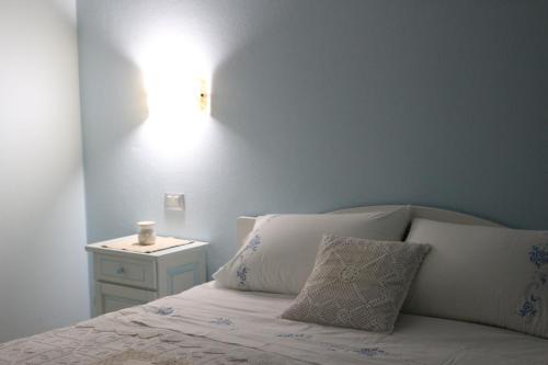 a bed with white pillows and a night stand with a lamp at Sardinia for you in Oristano