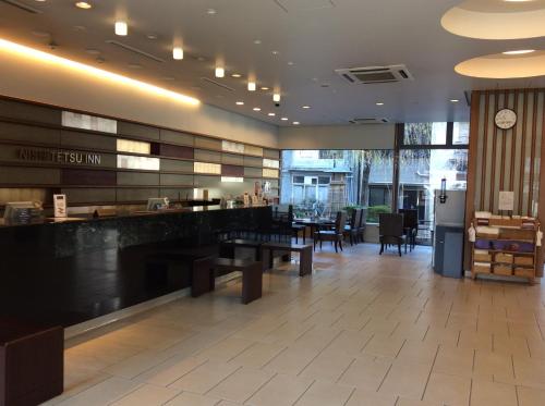 a lobby with tables and chairs and a clock on the wall at Nishitetsu Inn Kochi Harimayabashi in Kochi