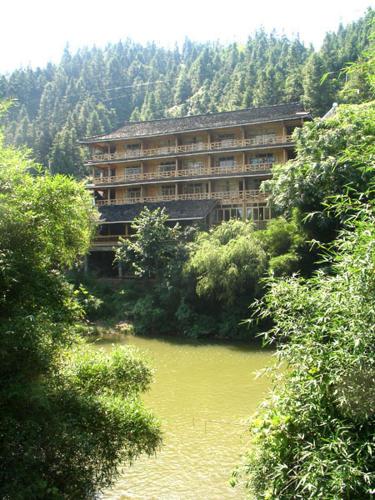 a large building next to a river with trees at Bridge View Boutique Guesthouse 望桥楼精品民宿 in Sanjiang