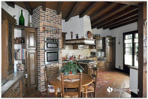 a kitchen with a table and a brick wall at Le Fuchier in Saint-Martin-de-Fressengeas