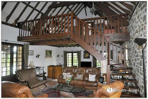 a living room with a couch and a wooden staircase at Le Fuchier in Saint-Martin-de-Fressengeas
