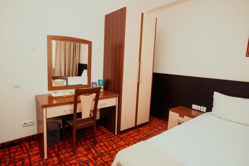 Schlafzimmer mit einem Schreibtisch, einem Bett und einem Spiegel in der Unterkunft Alma in Almaty