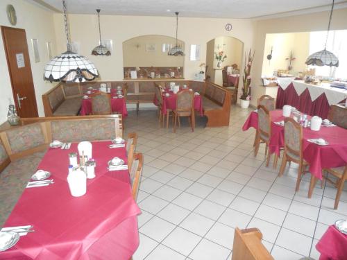 a restaurant with tables and chairs with red table cloth at Hotel Garni am Hechenberg in Mainz