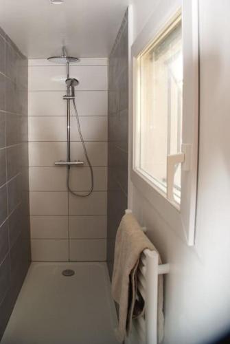La salle de bains est pourvue d'une douche, d'une serviette et d'une fenêtre. dans l'établissement Les Paillotes de Margaux, à Cantenac
