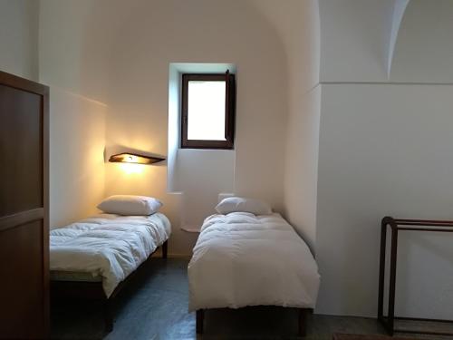 two beds in a small room with a window at 2 Gatti - Sogno in Pantelleria