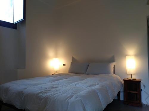 a bedroom with a large white bed with two lamps at 2 Gatti - Sogno in Pantelleria