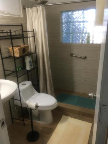 a bathroom with a toilet and a sink and a window at A Seascape Guest Room in Fajardo