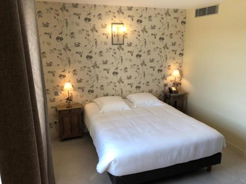 a bedroom with a white bed and two night stands at Le Prieuré de Boulogne in Tour-en-Sologne