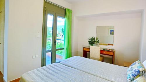 a bedroom with a bed and a desk and a window at Erodios Hotel in Karistos