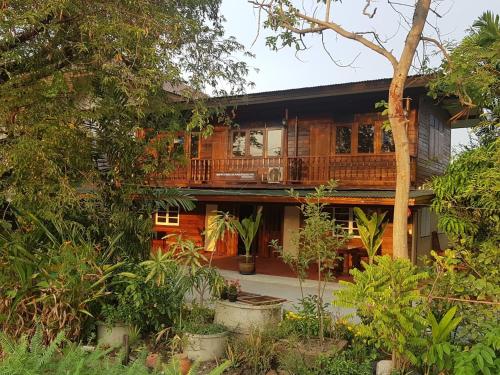 a wooden house with a balcony in a forest at Songthai Suvarnabhumi in Ban Khlong Si