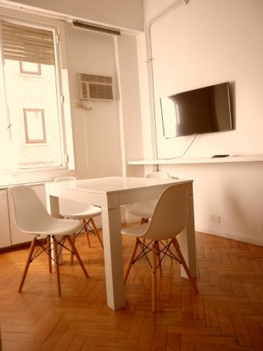 a white table and chairs in a room with a tv at Excelente departamento en Retiro in Buenos Aires