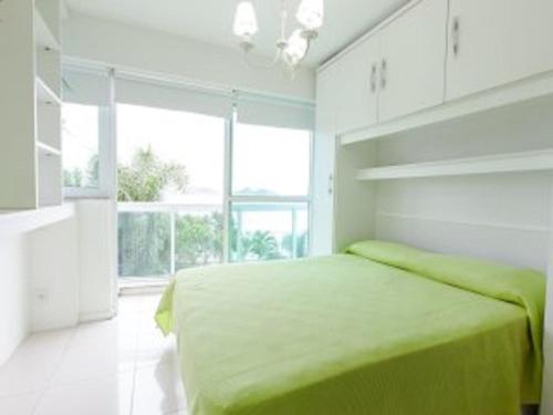 1 dormitorio con cama verde y ventana grande en Excelente apartamento beira mar en Río de Janeiro