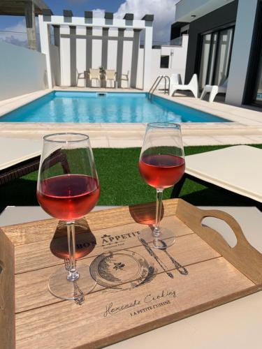 two glasses of wine on a wooden tray next to a pool at Obidos House with private pool in Bairro
