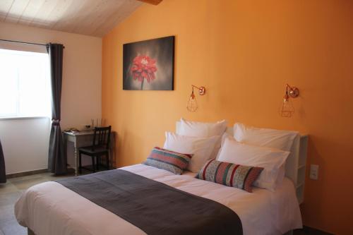 a bedroom with a large bed with orange walls at DOMAINE FORVENT in Saint-Julien-de-Peyrolas