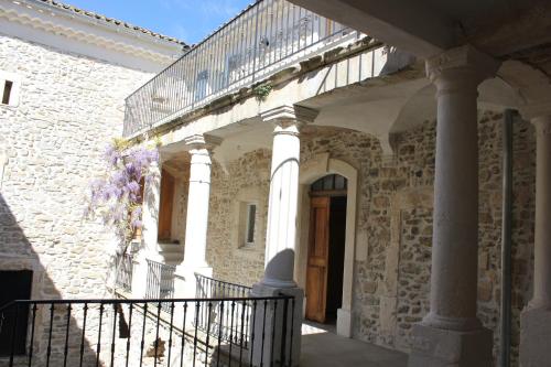 a stone building with a balcony and a staircase at DOMAINE FORVENT in Saint-Julien-de-Peyrolas