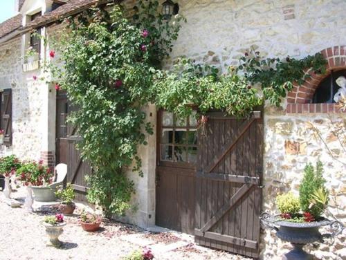 a house with a wooden door and flowers on it at La Petite Ferme in Vouzeron