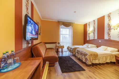 a hotel room with two beds and a flat screen tv at Hotel Doris in Oborniki