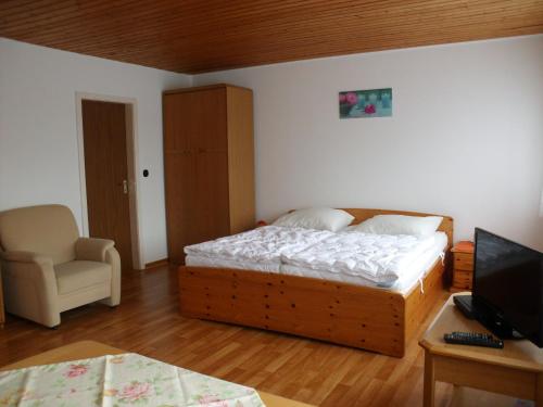 a bedroom with a bed and a chair and a television at Haus Hopp - Bungalow in Dahme