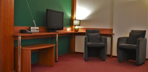 a room with two chairs and a desk with a television at Hotel Złote Dęby in Warsaw