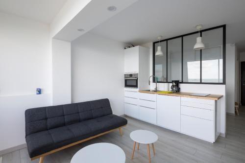 un salon avec un canapé noir et une cuisine dans l'établissement Ker Romain - Studio - Vue Mer 180 degres, à Saint-Malo