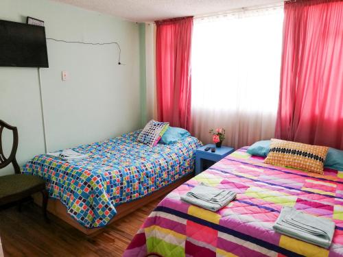 a bedroom with two beds and a window with red curtains at Casa Hotel en Chiquinquirá in Chiquinquirá