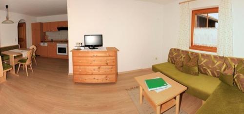 ein Wohnzimmer mit einem grünen Sofa und einer Küche in der Unterkunft Schuistlhof in Sillian
