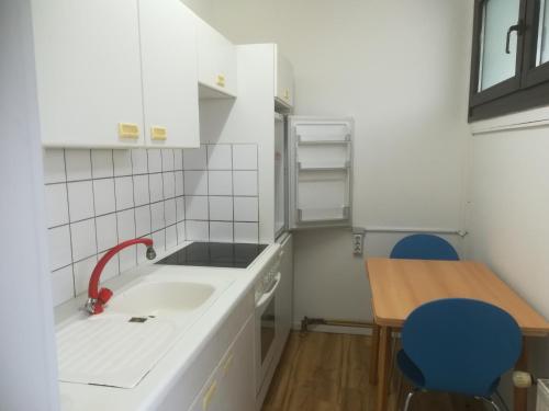 une cuisine avec un évier et une table avec des chaises bleues dans l'établissement Hannover Messe-Wohnung, à Hanovre