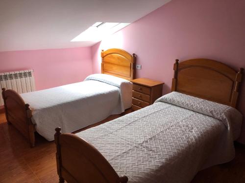 2 camas en una habitación con paredes rosas en B&B O Barqueiro, en O Barqueiro