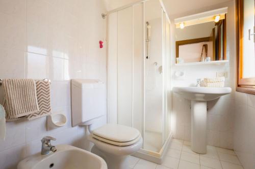 a white bathroom with a toilet and a sink at Residence Cristallo in Caorle