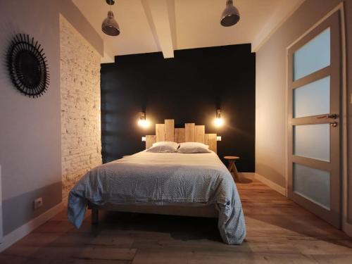 - une chambre avec un grand lit et une tête de lit noire dans l'établissement Le bon'appart - 50m de la cathédrale, à Montauban