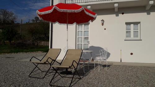 a table and chairs and an umbrella in front of a house at B&B Mermaid n 16/a in Treiso