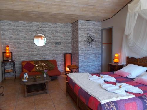a hotel room with a bed and a couch at Le Clos des Palmiers in Saint-ouen-dʼAunis
