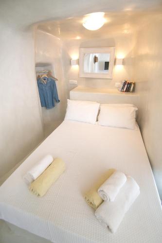 a white bed in a small room with towels on it at White Cave House in Oia