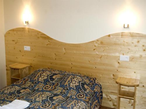 a bedroom with a bed with a wooden wall at Hotel de France in Chaudeyrac