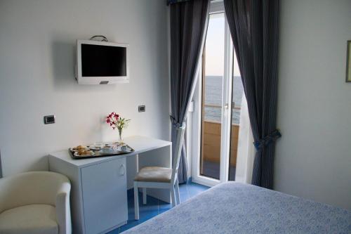 a bedroom with a bed and a desk and a window at Hotel La Sorgente in Savelletri di Fasano