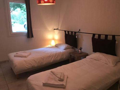 two beds in a room with a lamp and a window at Le Domaine du Thronnet in Figanières
