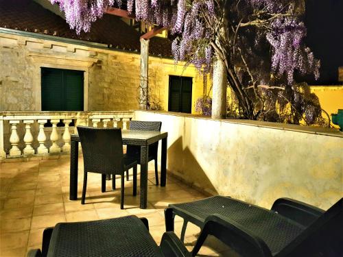 une table et des chaises sur une terrasse avec des fleurs violettes dans l'établissement Medulić Palace Rooms & Apartments, à Šibenik