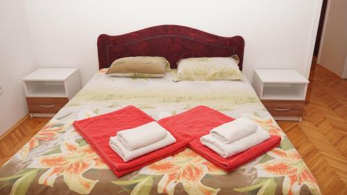 a bed with red and white towels on it at Apartmani Abeona in Budva