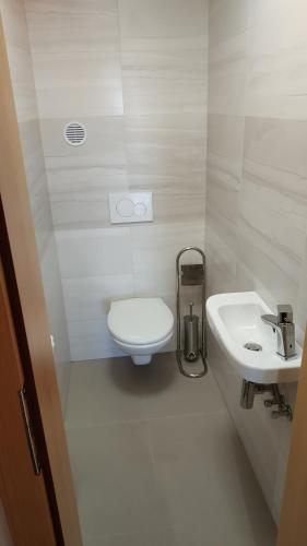 a white bathroom with a toilet and a sink at Bílá hora Štramberk in Štramberk