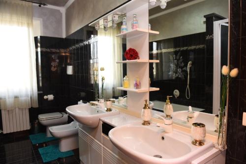 a bathroom with two sinks and a toilet and a mirror at Casa Dante in Romano di Lombardia