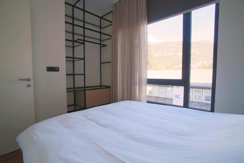 una camera con un letto bianco e una grande finestra di Luxury Home in Tivat Centre w/ Parking - 2Br Near Porto Montenegro a Tivat
