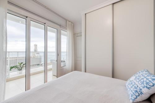 - une chambre avec un lit blanc et une vue sur l'océan dans l'établissement Living Las Canteras Homes - BEACH HOME, à Las Palmas de Gran Canaria