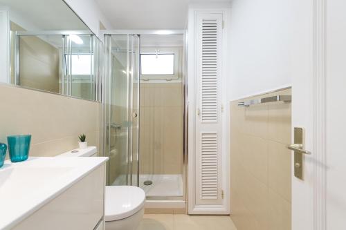 een witte badkamer met douche en toilet bij Living Las Canteras Homes - BEACH HOME in Las Palmas de Gran Canaria